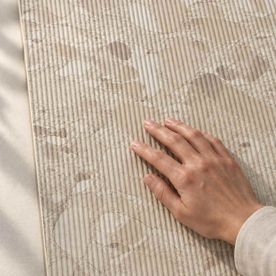 Hand touching the fine ribbed matt surface and greige stone-effect pattern of Gradia Greige Decor wall tile – product render.