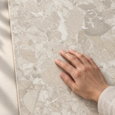 Hand touching the smooth matt surface and stone-effect pattern of Gradia Greige Matt porcelain tile – product render.